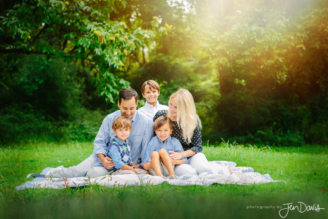 A family sitting on a blanket in a park during summer in Princeton NJ