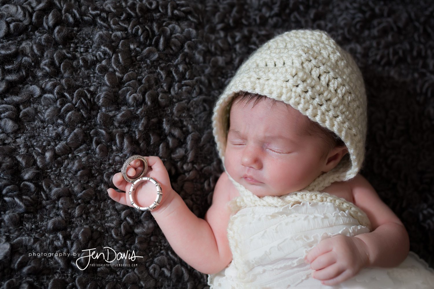 Baby with cream bonnet and wedding rings