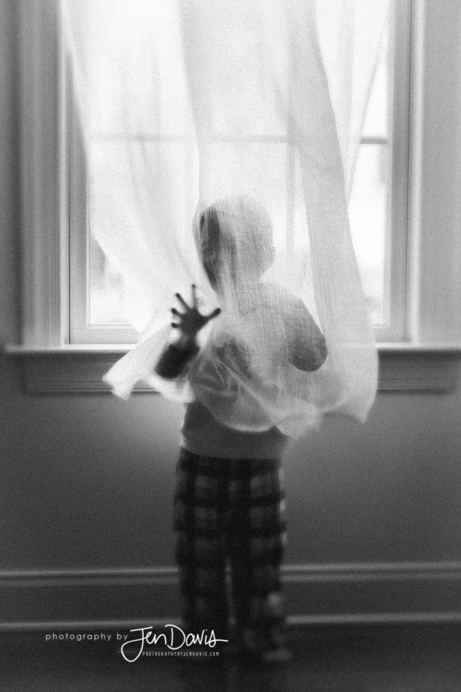 black and white film of little boy with window drape