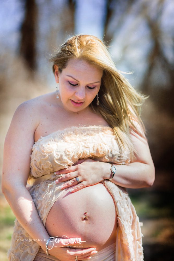 Pregnant woman showing her belly in the woods