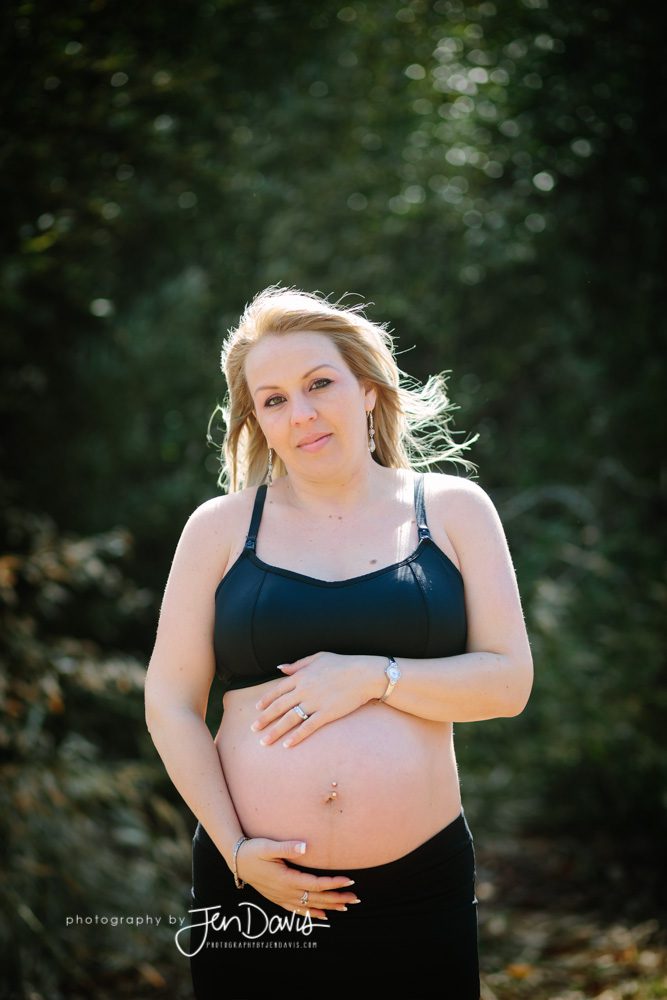 Pregnant woman wearing black in the woods showing her belly