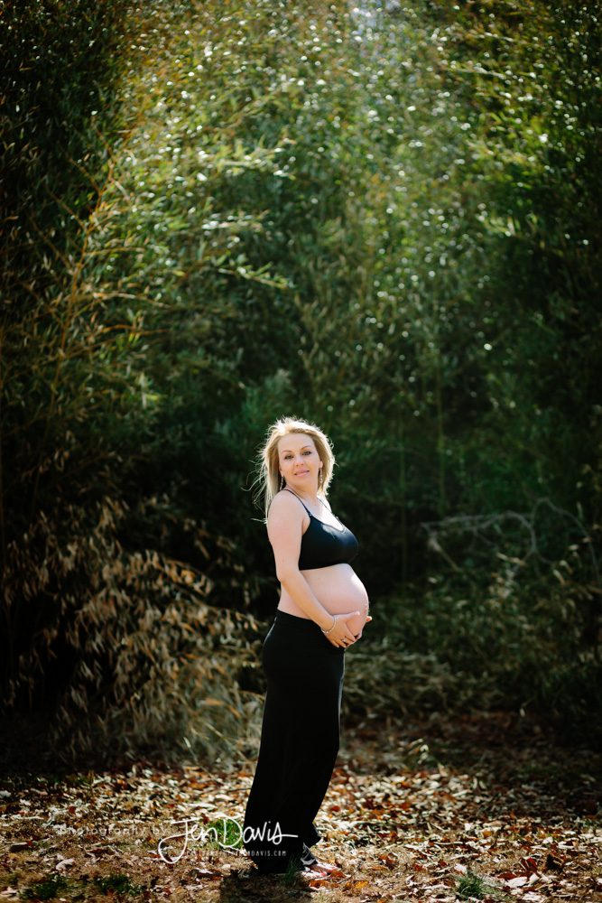 Pregnant woman wearing black in the woods showing her belly