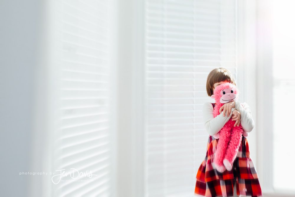 Girl with stuffed monkey hiding her face
