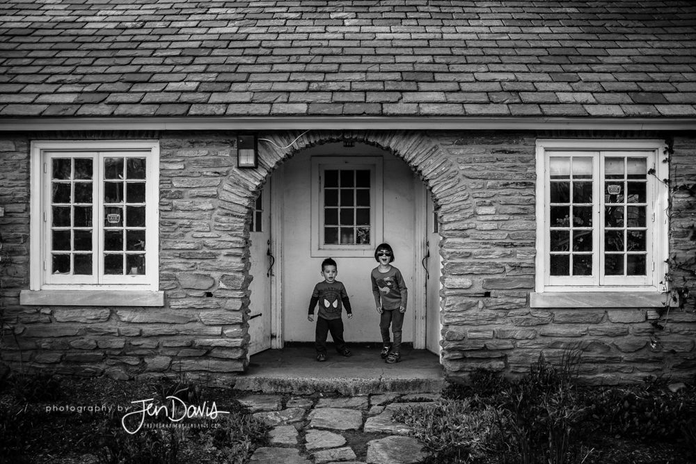 two kids in front of a house in black and white