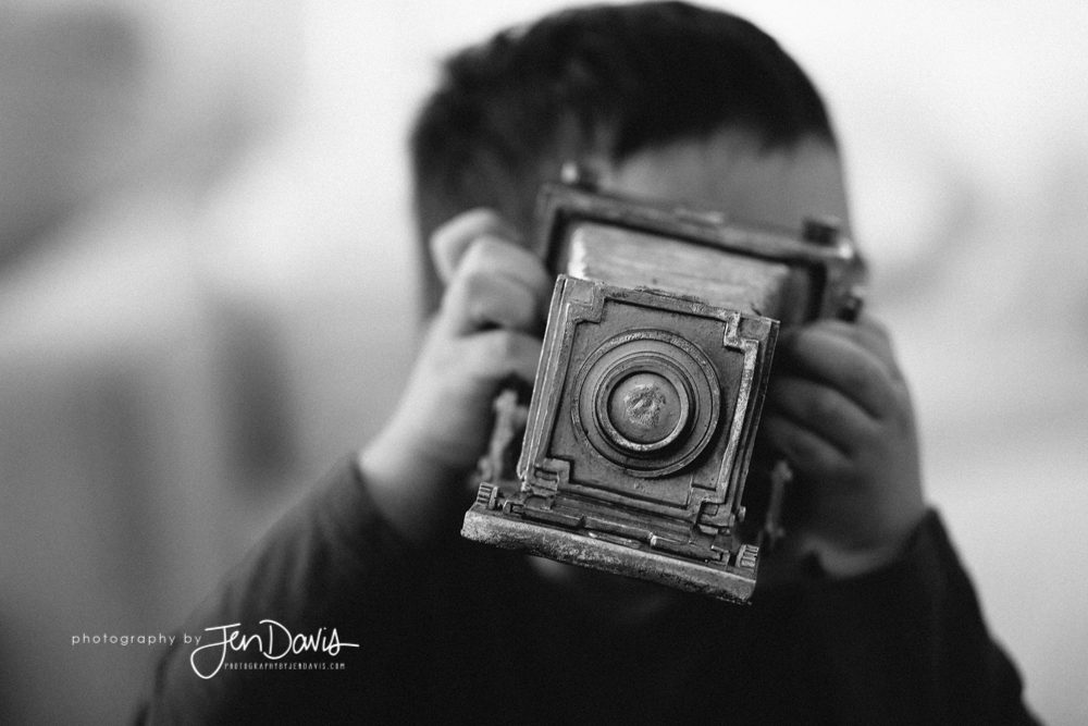 black and white of boy holding a camera