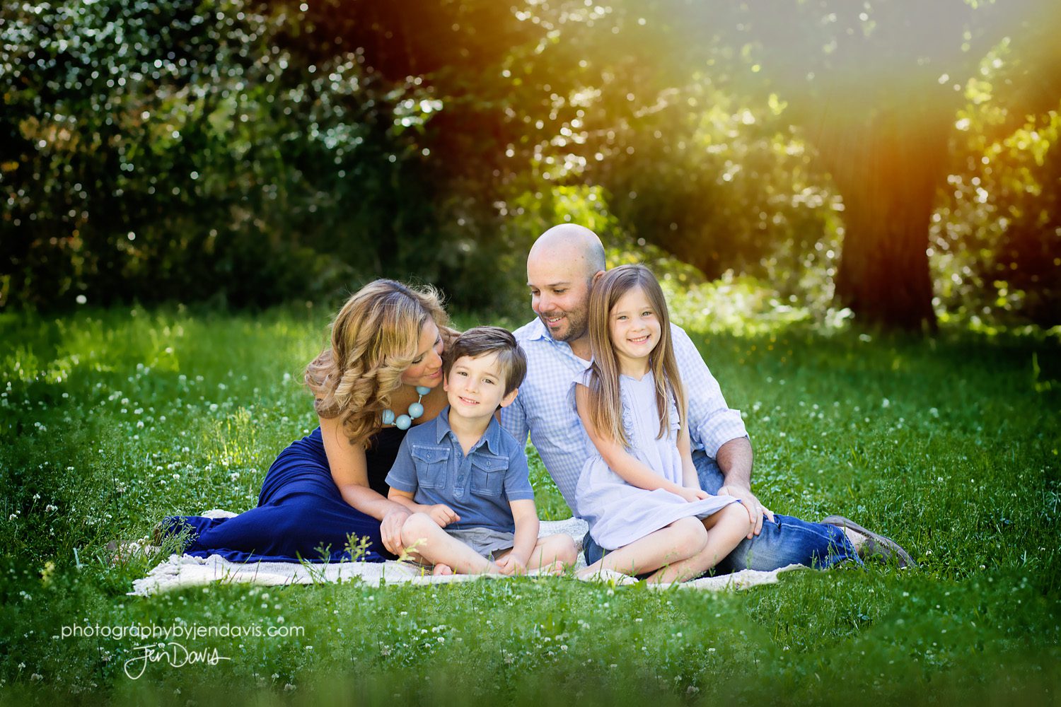 Family of 4 sitting on a blanket in the meadow