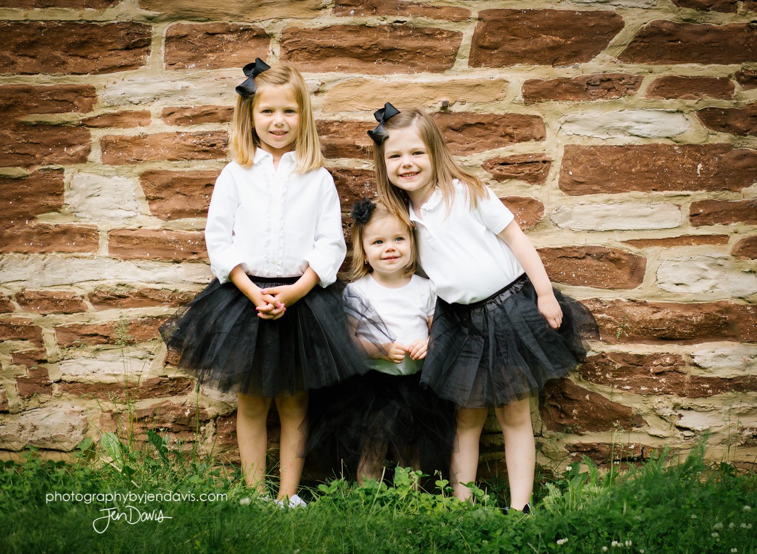 sisters by a brick wall in black tutus