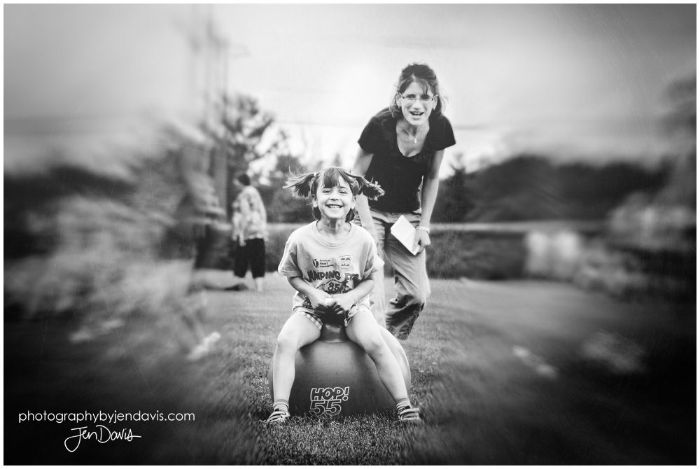 girl hopping on ball in black and white