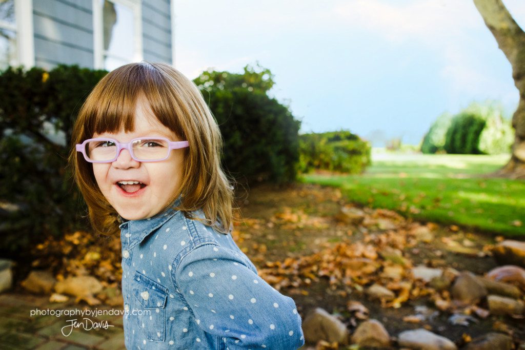 Little girl with glasses laughing outside