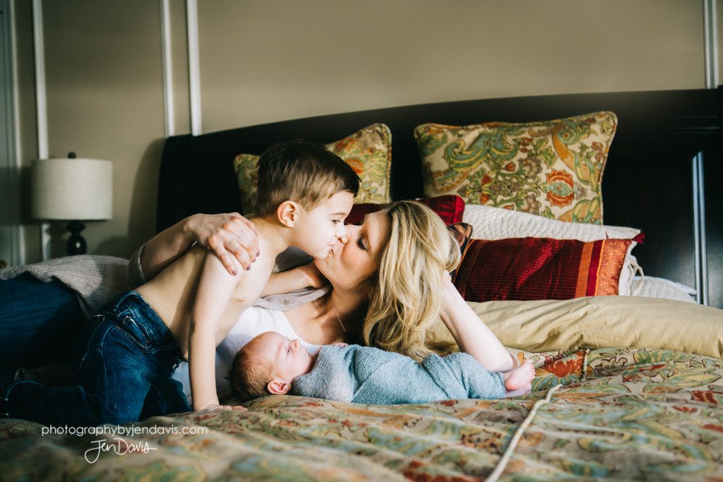 mother on bed with her sons and a baby