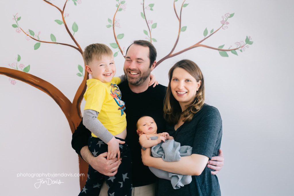 a new family in front of tree decal in the nursery