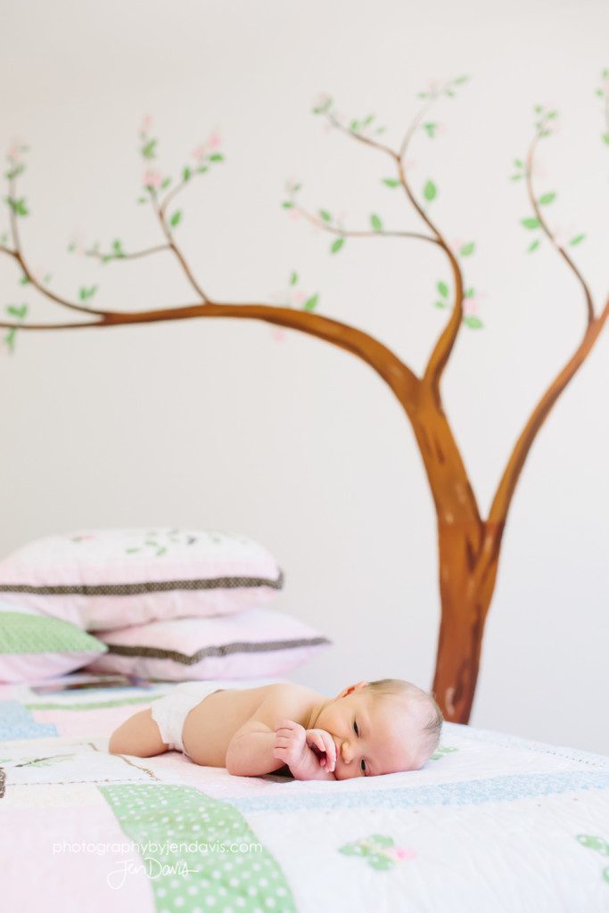 baby girl on a bed in front of tree wall decal