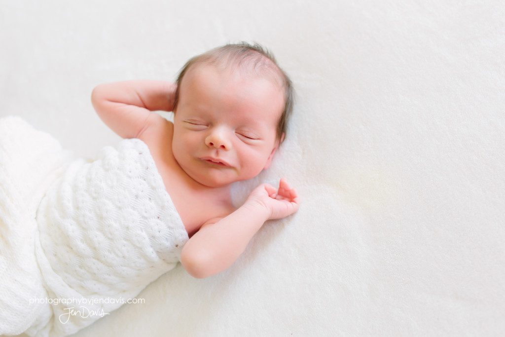 baby wrapped in white blanket on white bed