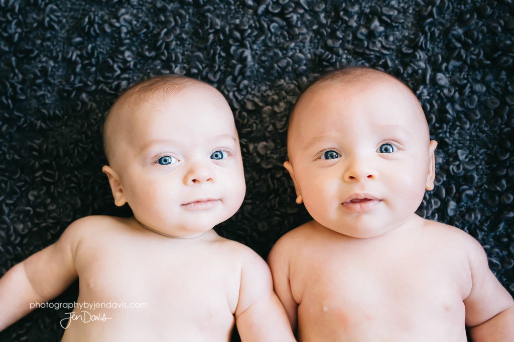 twins smiling on grey blanket