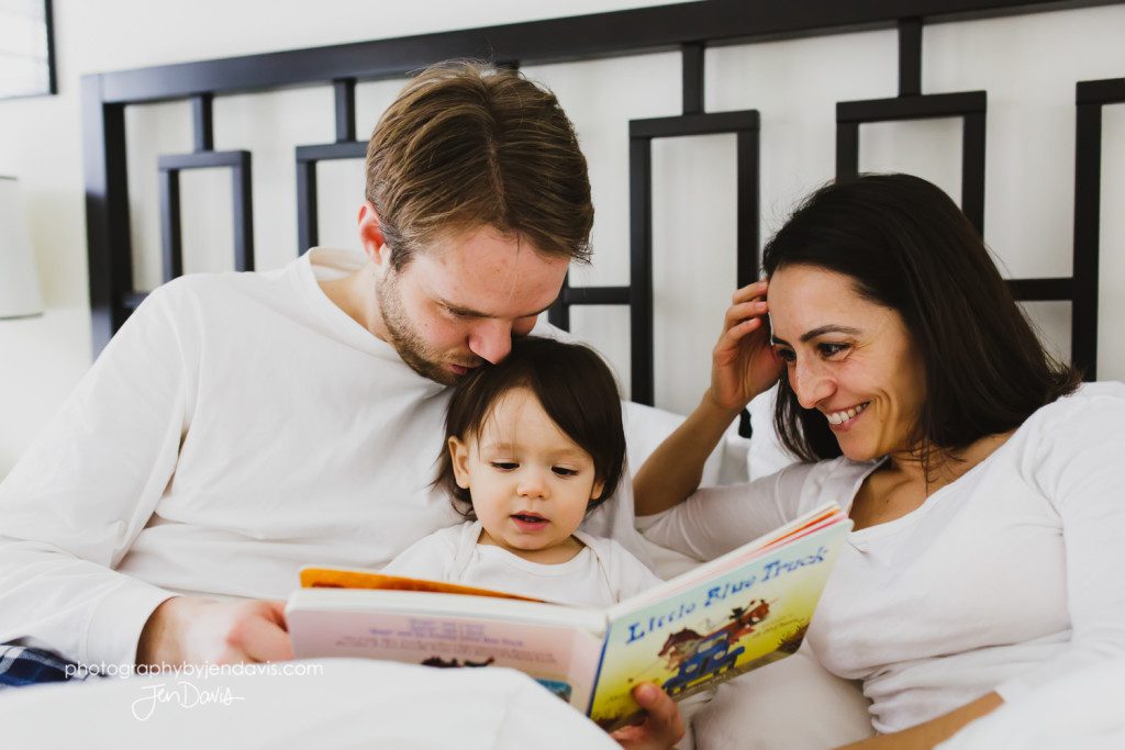 Mom and Dad and 1 year old boy reading in bed