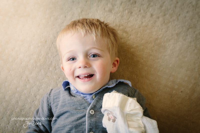 boy smiling on floor with blanket