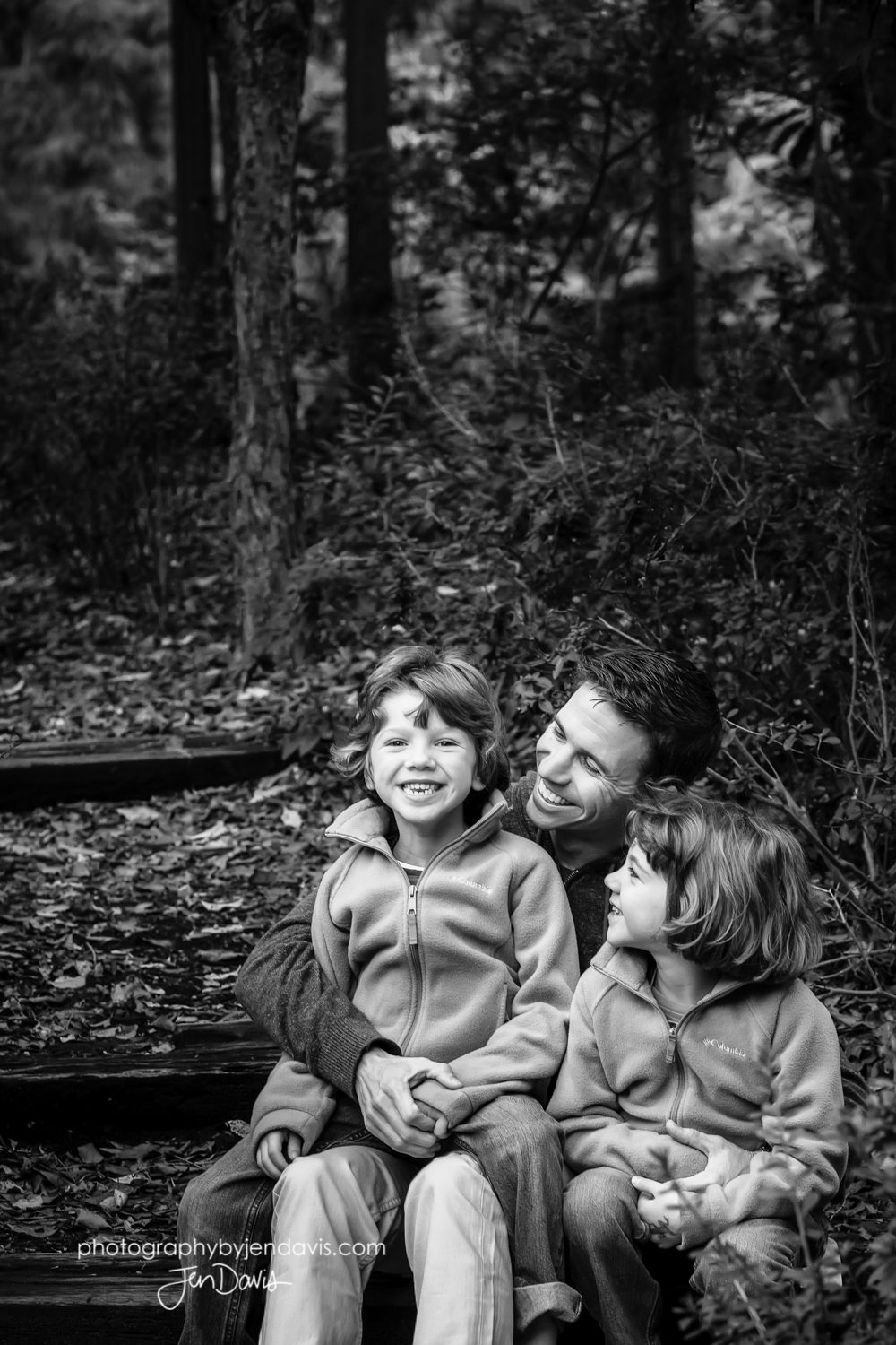 dad with his two daughters laughing in black and white