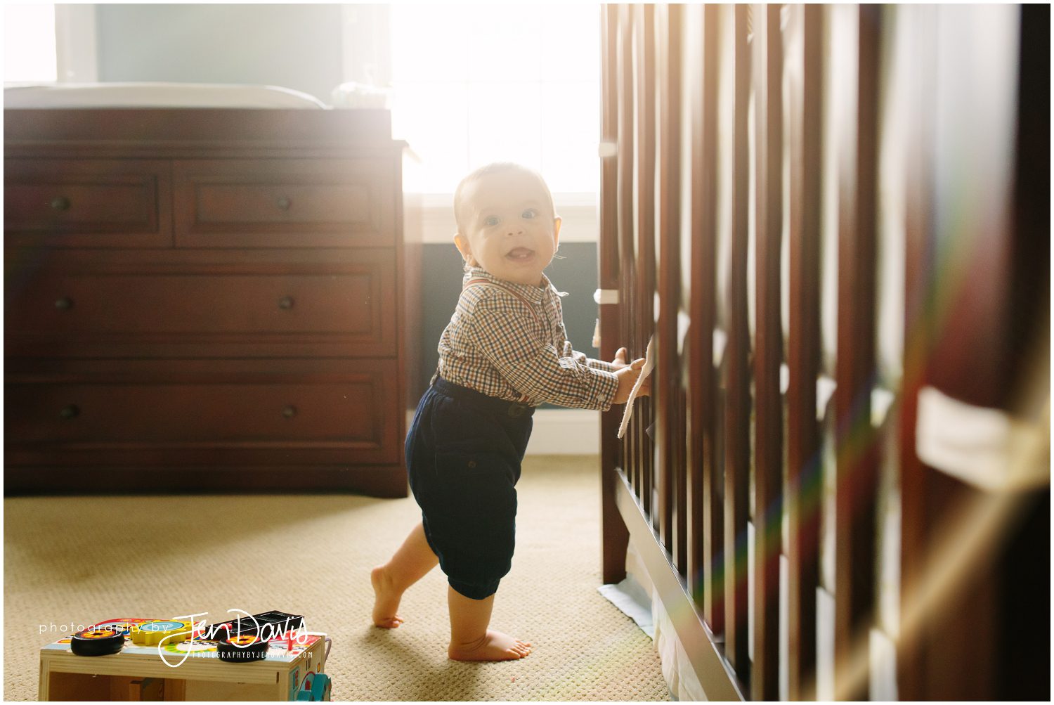 1 year old boy holding onto the crib