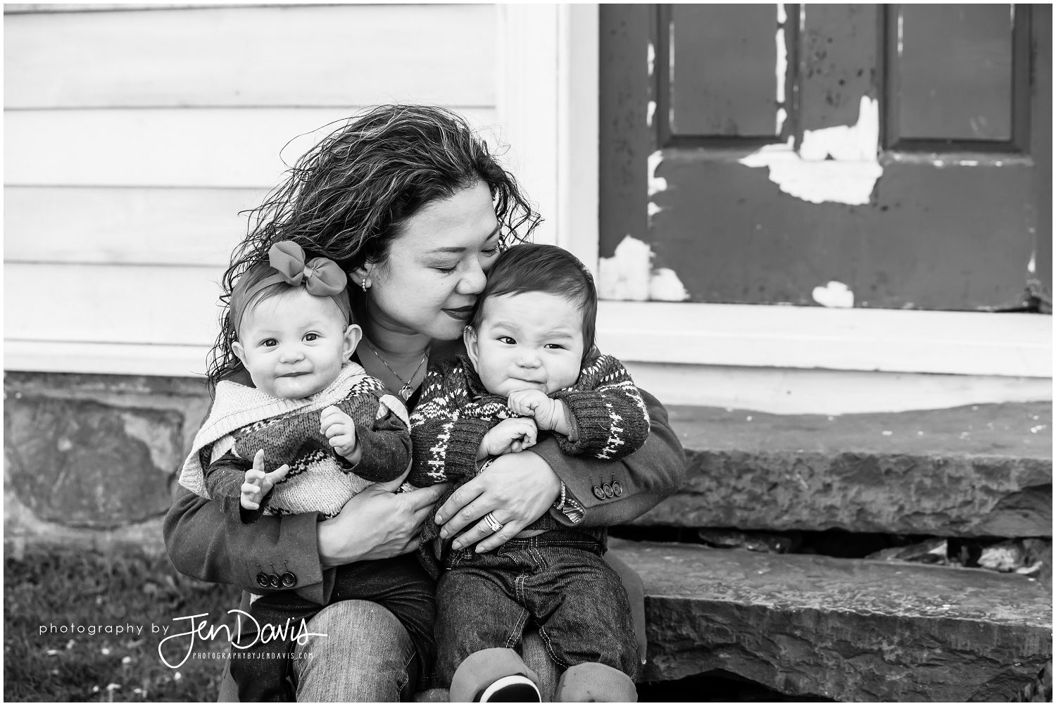Mom holding 7 month old twins kissing them.