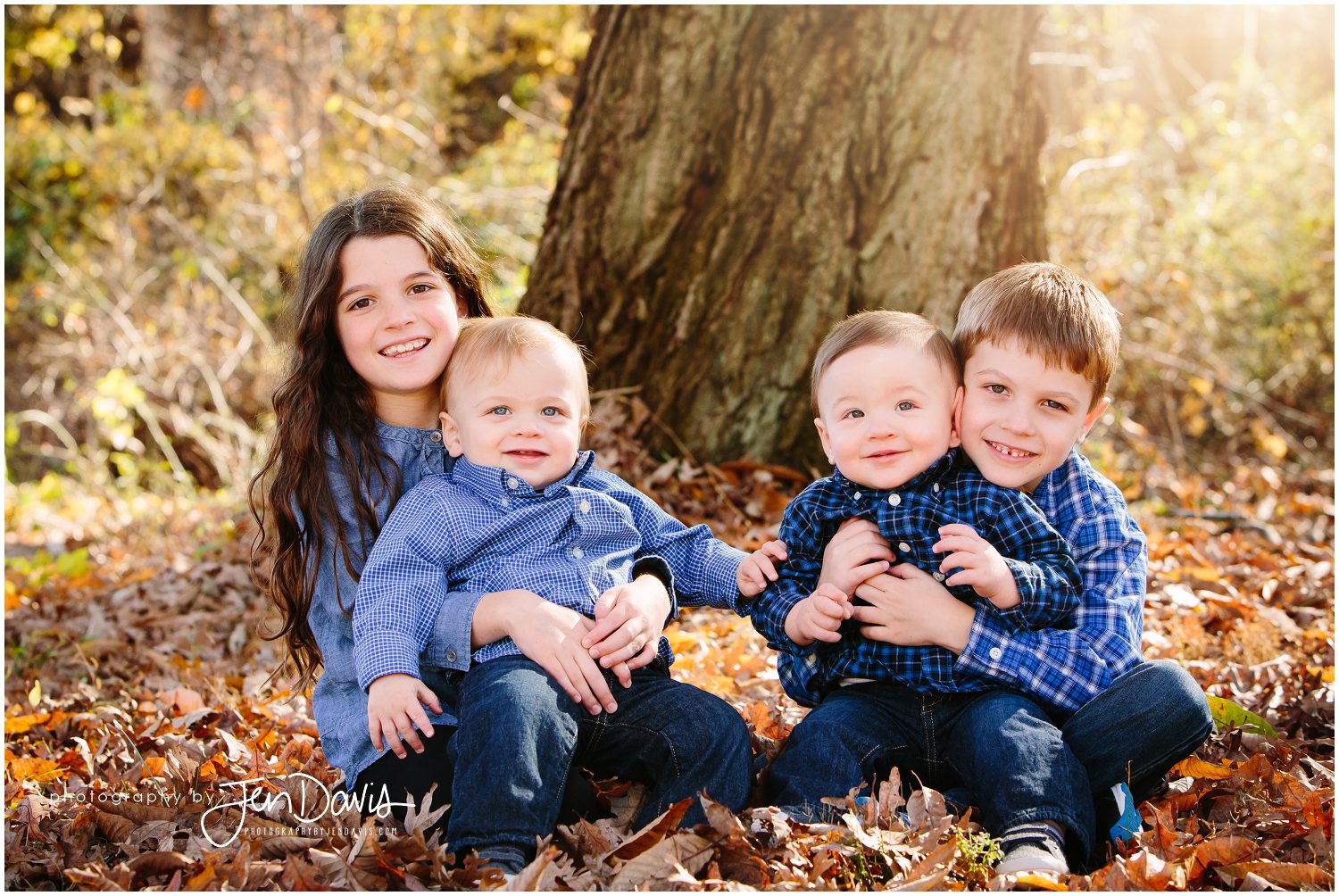 4 Siblings sitting together in the leaves