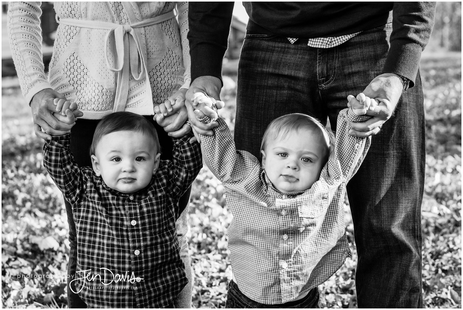black and white of 1 year old twins held up by their parents