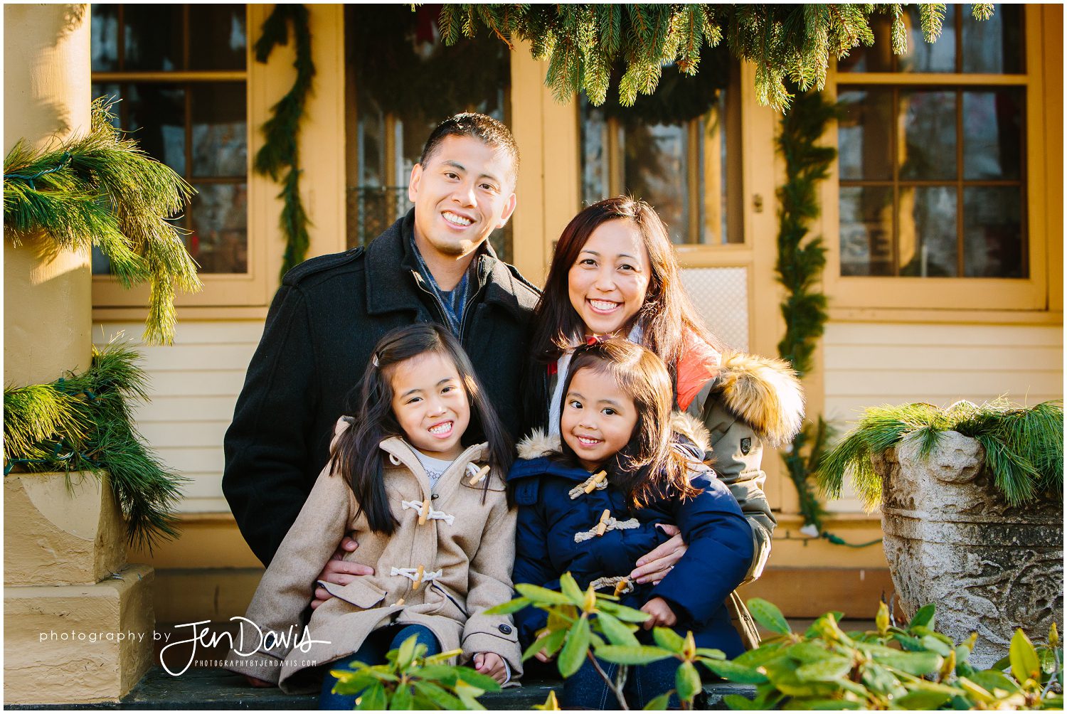 Family smiling in front of house decorated for Christmas