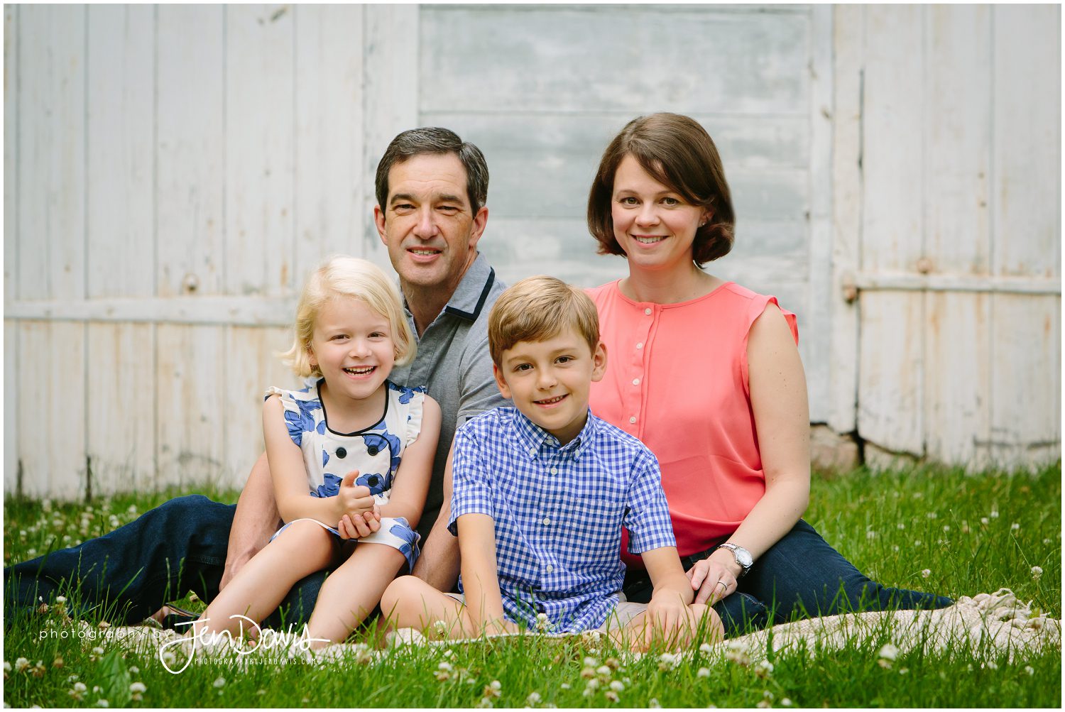 family posed smiling by a barn