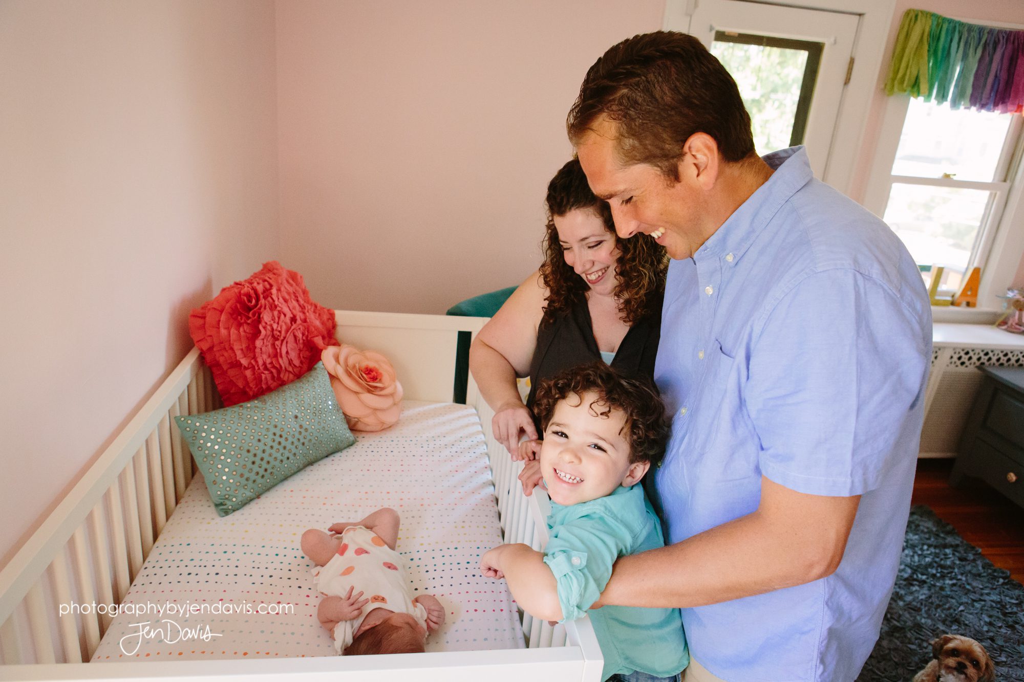 Familyof 4 looking at baby in crib